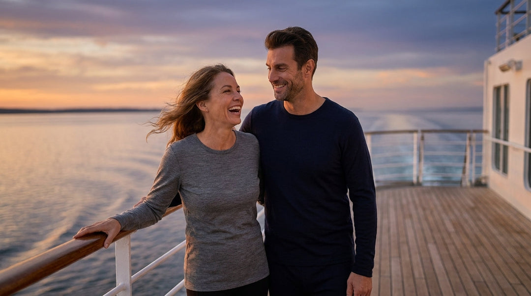 Couple in merino wool long sleeve tops at a cruise ship deck rail at dusk as the evening breeze picks up