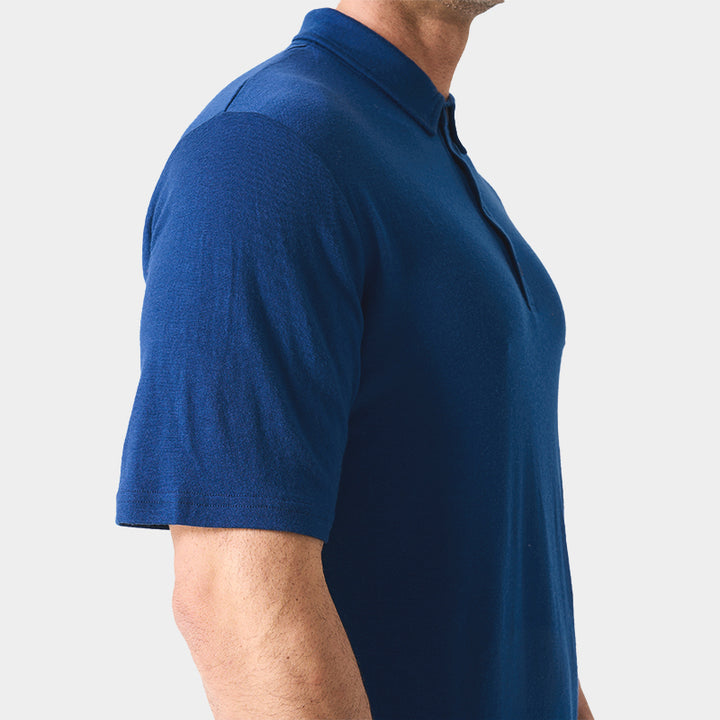 Male model wearing white merino wool polo shirt, featuring flexible fit, short sleeves, three-button placket, and stand-up collar for sun protection.
