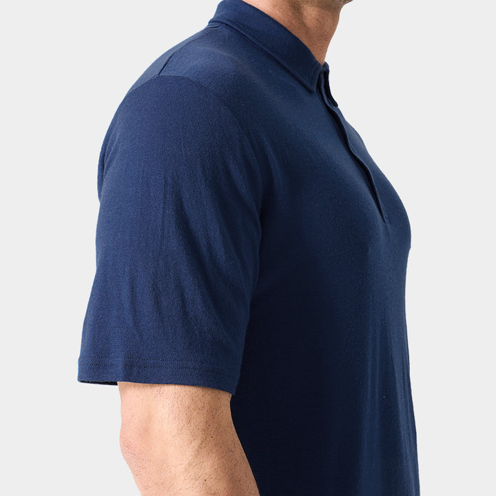 Male model wearing white merino wool polo shirt, featuring flexible fit, short sleeves, three-button placket, and stand-up collar for sun protection.
