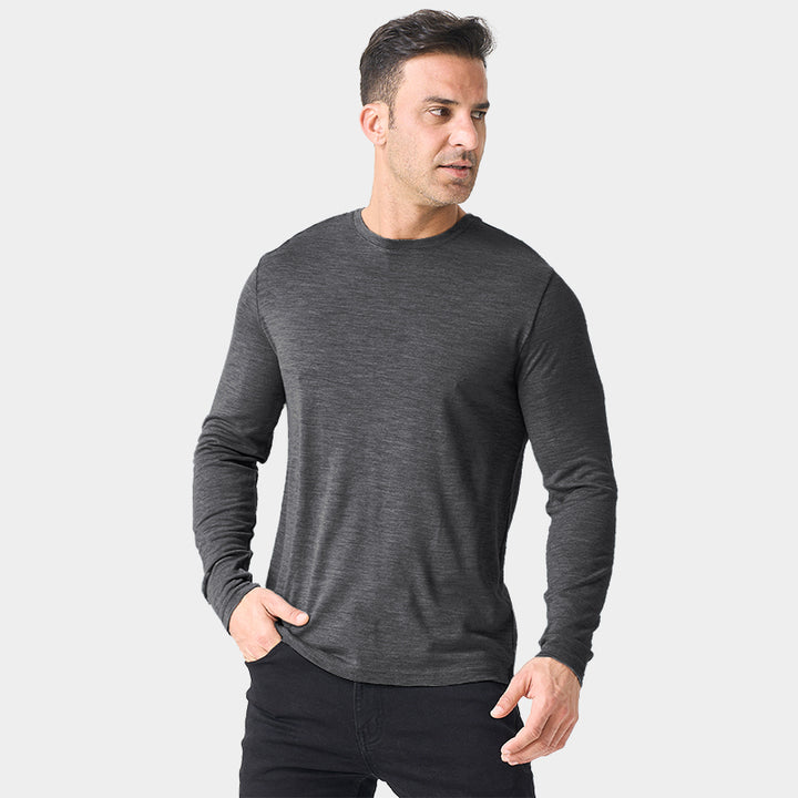 Male model wearing a lightweight Merino wool long sleeve crew base layer top, breathable and comfortable, shown in dark grey heather.
