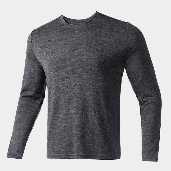 Male model wearing a lightweight Merino wool long sleeve crew base layer top, breathable and comfortable, shown in dark grey heather.