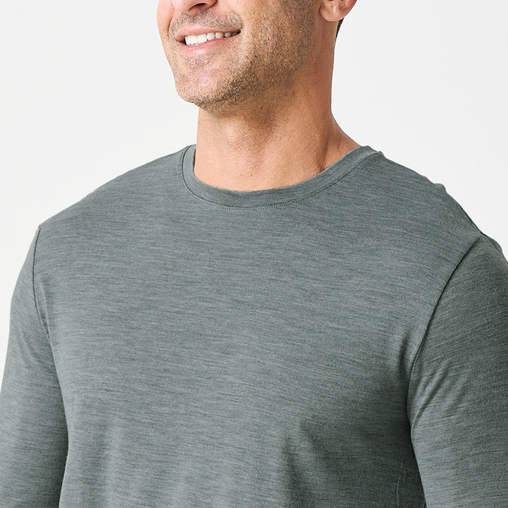 Male model wearing a lightweight Merino wool long sleeve crew base layer top, breathable and comfortable, shown in grey heather.