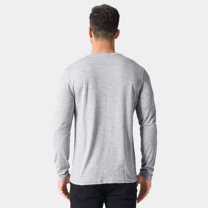 Male model wearing a lightweight Merino wool long sleeve crew base layer top, breathable and comfortable, shown in light grey heather.