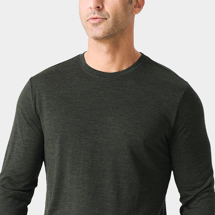 Male model wearing a lightweight Merino wool long sleeve crew base layer top, breathable and comfortable, shown in moss green heather.