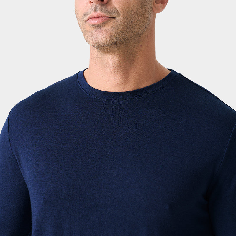 Male model wearing a lightweight Merino wool long sleeve crew base layer top, breathable and comfortable, shown in navy.