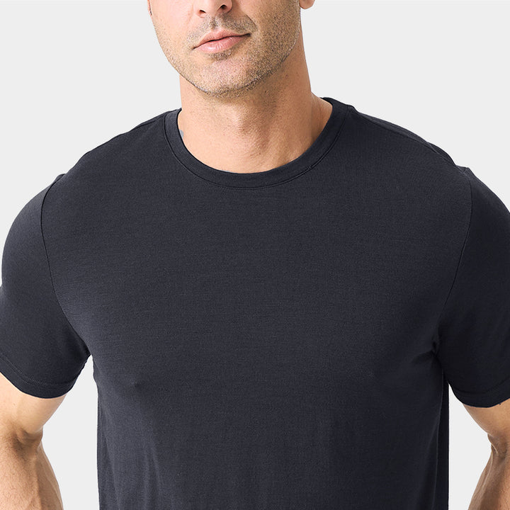 Male model wearing a lightweight Merino wool short sleeve crew t-shirt, breathable and moisture-wicking, shown in charcoal.