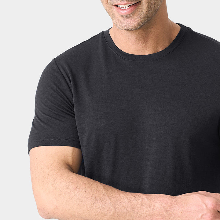 Male model wearing a lightweight Merino wool short sleeve crew t-shirt, breathable and moisture-wicking, shown in charcoal.
