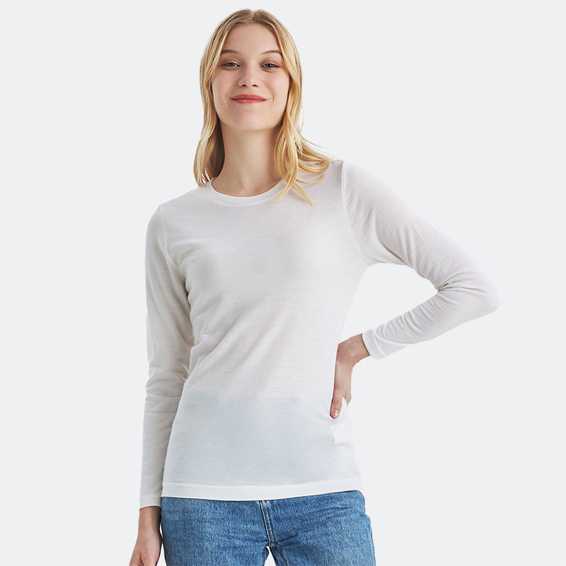 Famel model wearing a lightweight Merino wool long sleeve crew base layer top, breathable and comfortable, shown in natural cream.