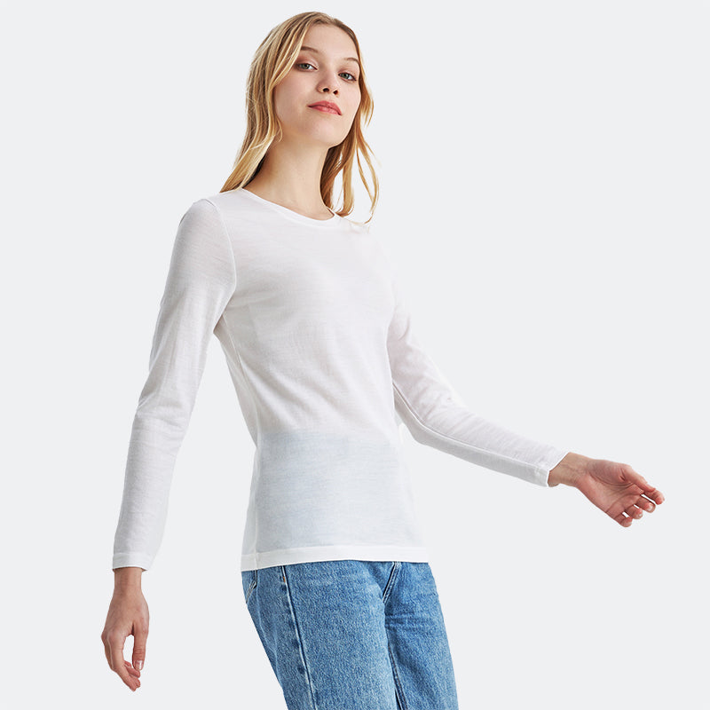 Famel model wearing a lightweight Merino wool long sleeve crew base layer top, breathable and comfortable, shown in natural cream.